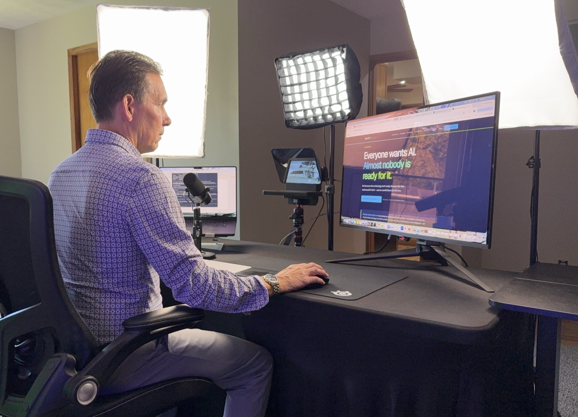 Billy Thomas at his desk, recording setup in a home office — monitor, microphone, teleprompter and softbox lighting
